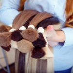 Woman holds hair extension equipment of natural hair. hair samples of different colors